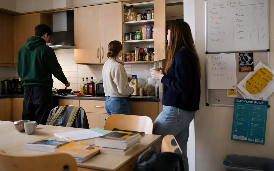 Students cooking and chatting in a shared student house kitchen in Birmingham.