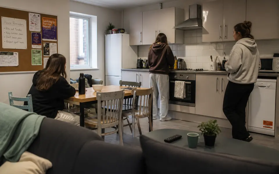 Shared student kitchen and living area in Nottingham with several students cooking and talking.