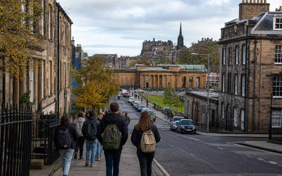 View over central Edinburgh with historic buildings, a university campus area and students walking along a city street.
