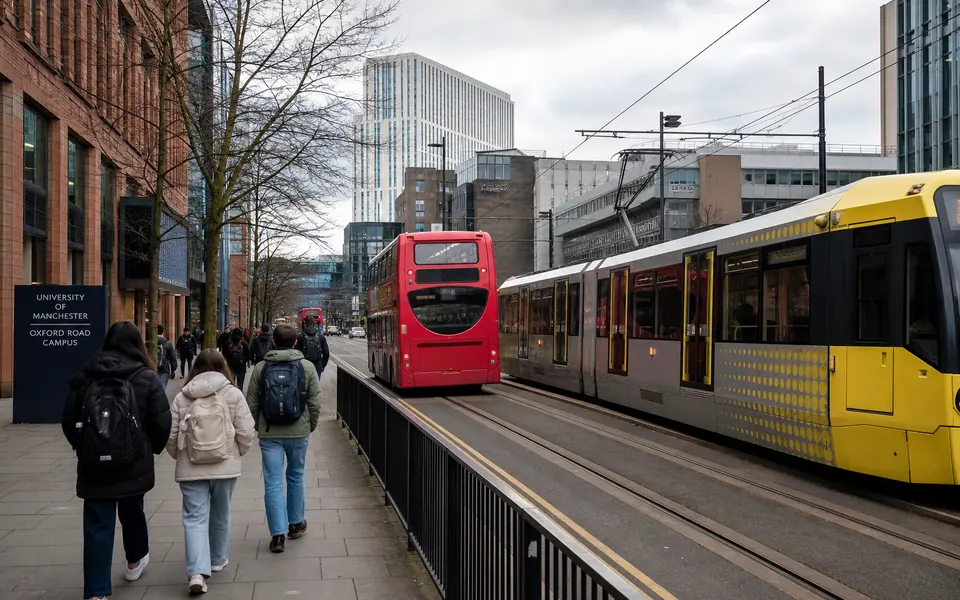 Oxford Road in Manchester with buses, a tram line and students walking near university buildings.