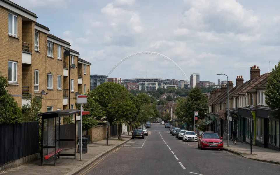 Residential street in Wembley or Harrow with mid-rise brick flats and the Wembley Stadium arch in the distance.